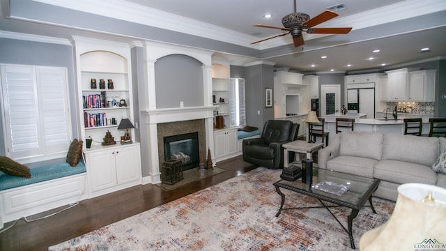 living room featuring ceiling fan, dark hardwood / wood-style floors, ornamental molding, and built in features