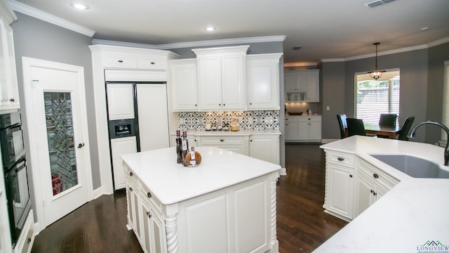 kitchen with pendant lighting, sink, decorative backsplash, a kitchen island, and white cabinetry