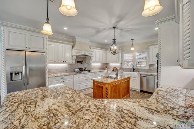 kitchen with appliances with stainless steel finishes, premium range hood, light stone counters, decorative light fixtures, and white cabinets