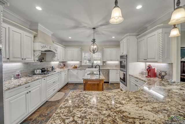 kitchen featuring light stone countertops, backsplash, a kitchen island with sink, decorative light fixtures, and white cabinets