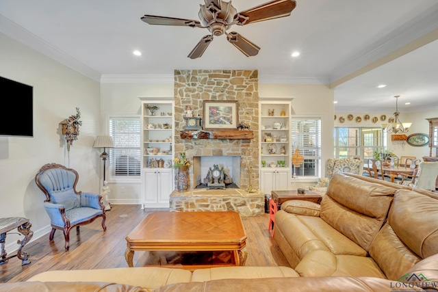 living room featuring a fireplace, ornamental molding, built in features, and light wood-type flooring