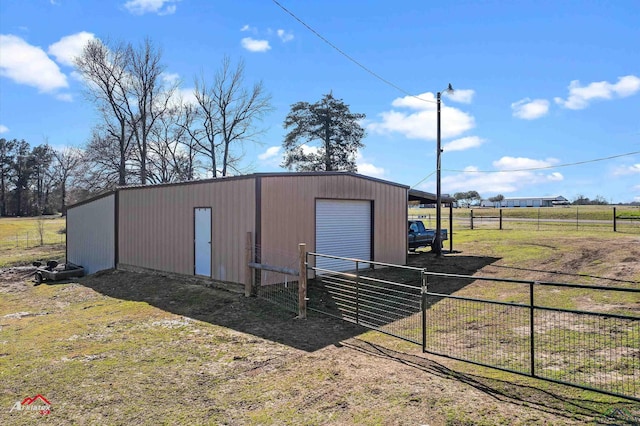 view of pole building with driveway, a rural view, fence, and a lawn