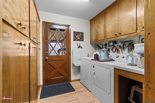 laundry area featuring baseboards, cabinet space, light wood-style flooring, and washing machine and clothes dryer