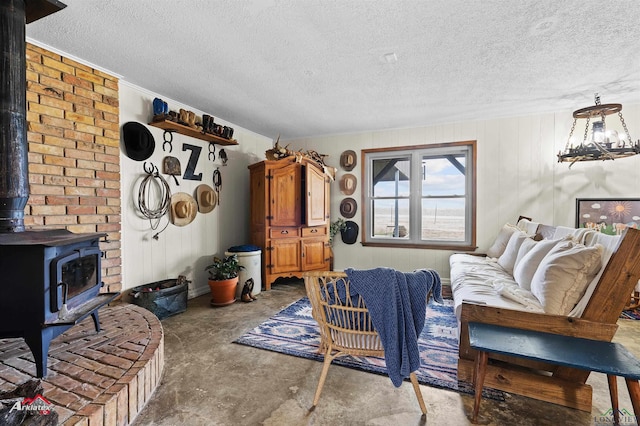 living area featuring a textured ceiling, ornamental molding, a wood stove, and concrete flooring