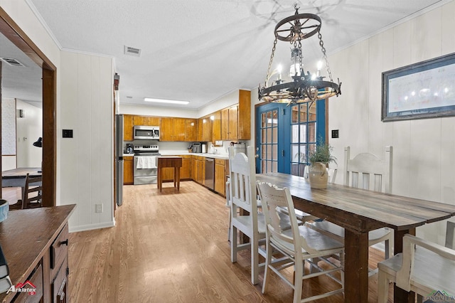 dining room with crown molding, a textured ceiling, visible vents, and light wood-style floors