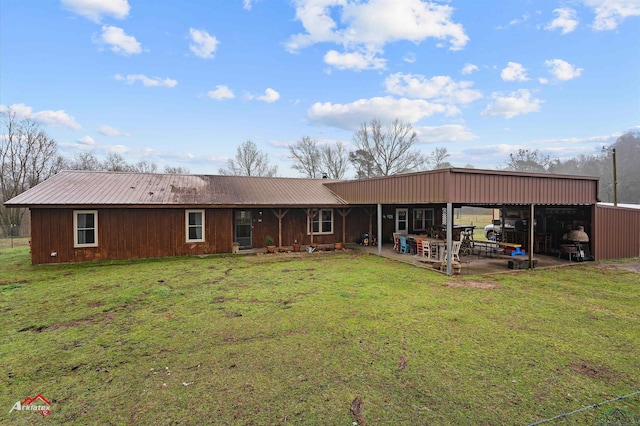 rear view of house featuring metal roof, a patio area, and a yard