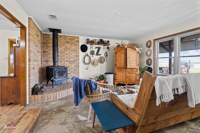 living room with a textured ceiling, visible vents, concrete floors, and a wood stove