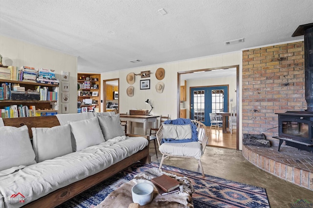 living room with built in features, french doors, visible vents, a wood stove, and a textured ceiling