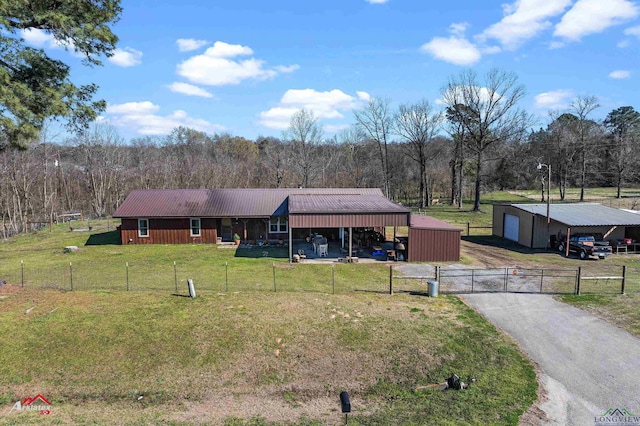 view of front of home featuring metal roof, an outbuilding, fence, a carport, and a front yard