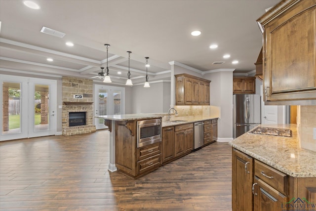 3363 Celebration Way, Longview, TX 75605 - kitchen featuring appliances with stainless steel finishes, ornamental molding, open floor plan, a brick fireplace, and a ceiling fan