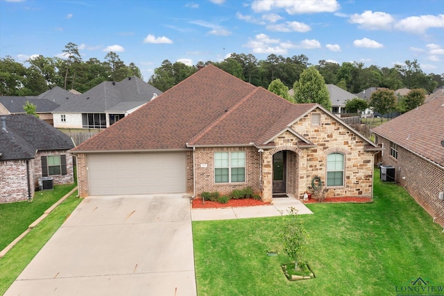 ranch-style home with concrete driveway, central AC unit, a front yard, and a garage