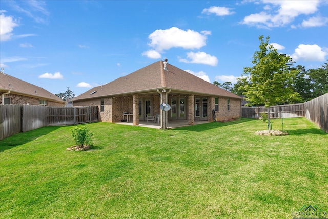 back of property featuring a fenced backyard, a yard, a patio area, and brick siding