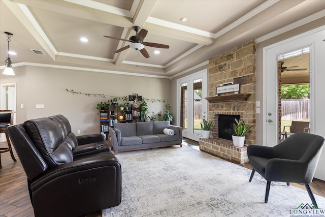 living room featuring beamed ceiling, plenty of natural light, a fireplace, and a ceiling fan