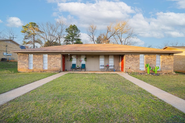 ranch-style house with covered porch, brick siding, a front yard, and cooling unit