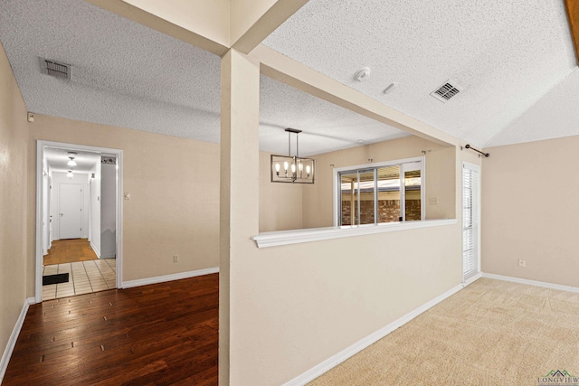 spare room featuring hardwood / wood-style flooring, a notable chandelier, and a textured ceiling