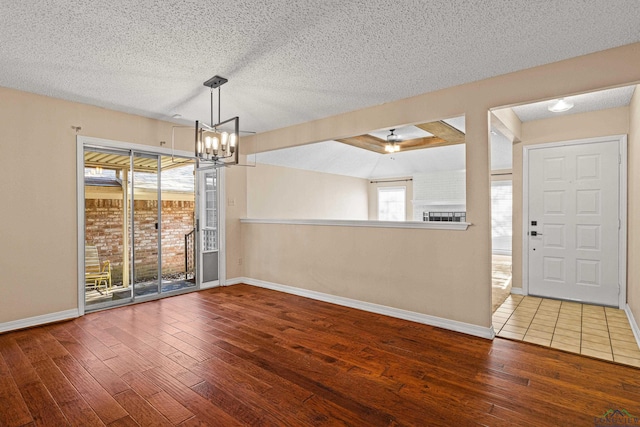 unfurnished dining area featuring hardwood / wood-style floors, a textured ceiling, and an inviting chandelier