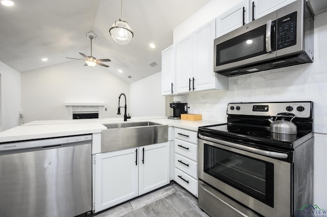 kitchen with light countertops, appliances with stainless steel finishes, vaulted ceiling, a sink, and a peninsula