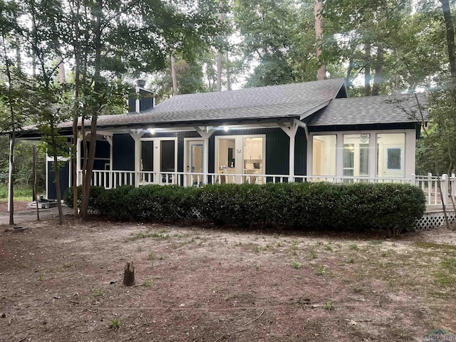 view of front of property with a porch, roof with shingles, and a chimney