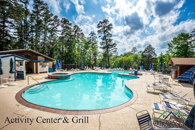 view of swimming pool featuring a patio area, a pool with connected hot tub, and fence