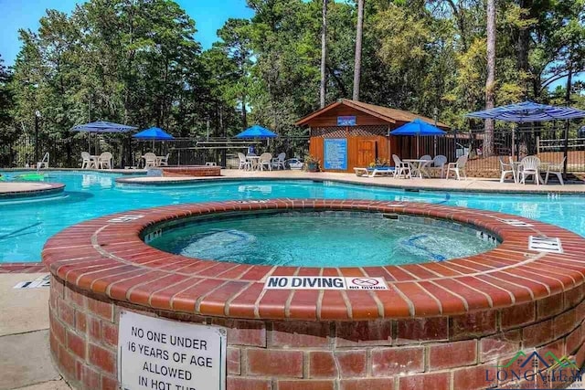 community pool featuring a patio area, fence, and a hot tub