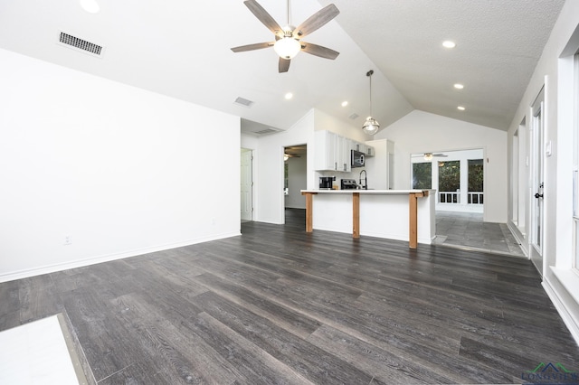 unfurnished living room featuring dark wood-style flooring, visible vents, a ceiling fan, a sink, and baseboards