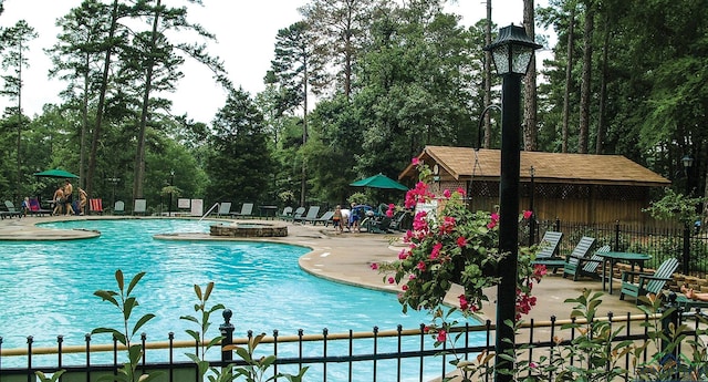 community pool with an outdoor fire pit, a patio area, and fence