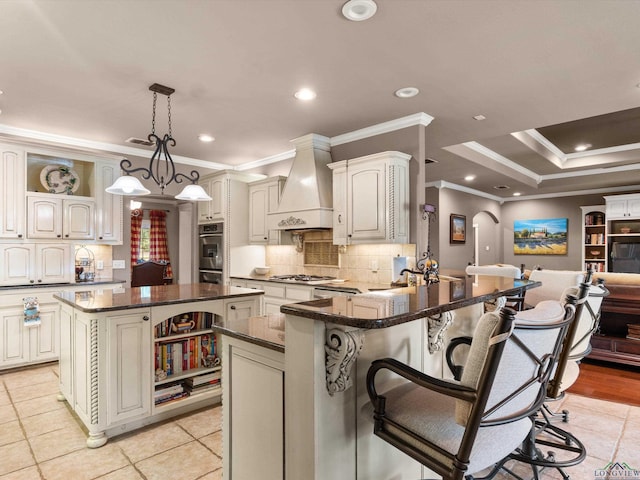 kitchen featuring kitchen peninsula, ornamental molding, custom range hood, a center island, and a breakfast bar area