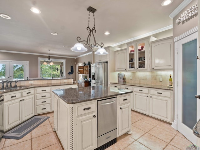 kitchen featuring sink, decorative backsplash, appliances with stainless steel finishes, decorative light fixtures, and a kitchen island