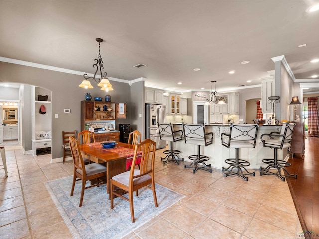 dining room with light tile patterned floors, an inviting chandelier, and crown molding