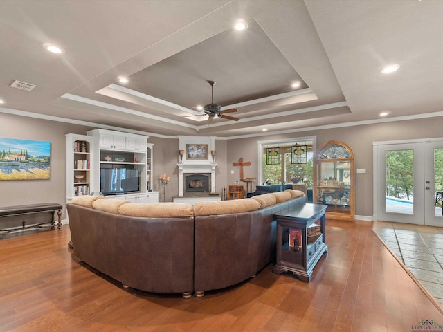 living room with plenty of natural light, light wood-type flooring, and a tray ceiling