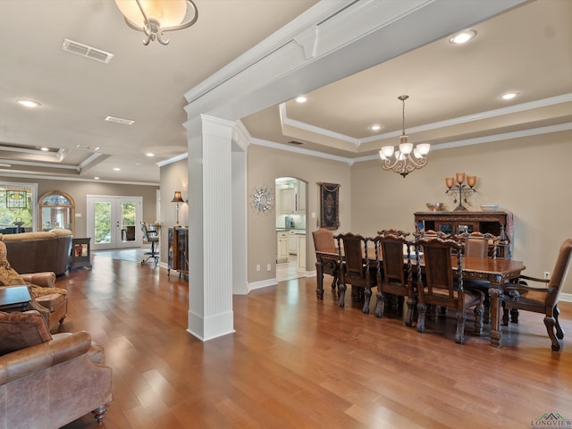 dining area featuring decorative columns, a raised ceiling, ornamental molding, and a chandelier