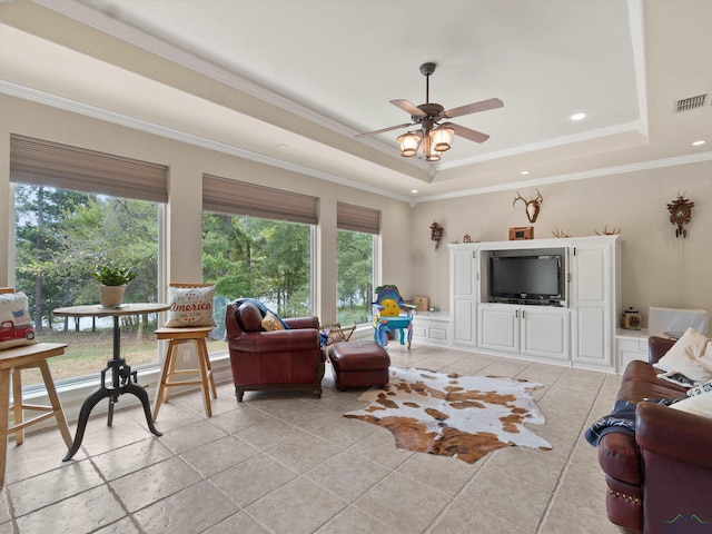 living room featuring a raised ceiling, ceiling fan, and ornamental molding