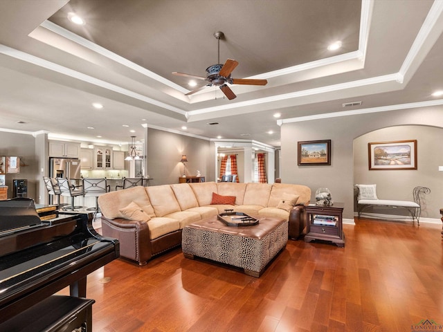 living room with a tray ceiling and ornamental molding