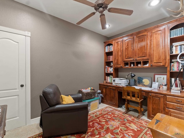 carpeted home office featuring ceiling fan and built in desk