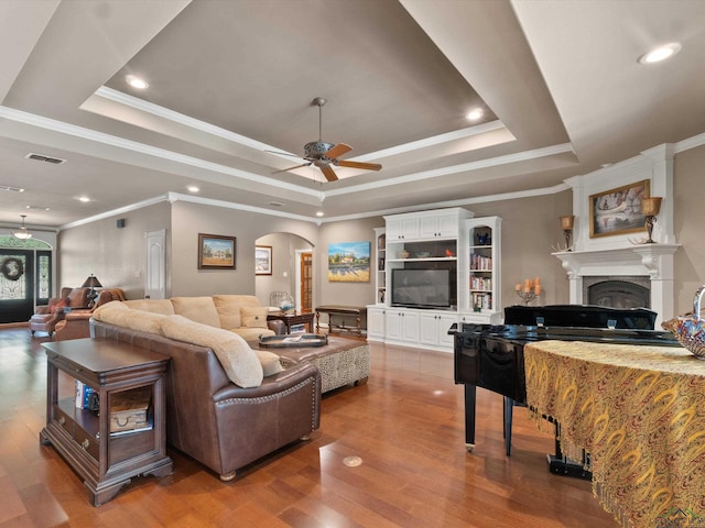 living room with hardwood / wood-style floors, a tray ceiling, ceiling fan, and crown molding