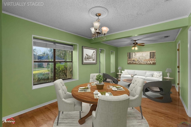 dining area with ceiling fan with notable chandelier, a textured ceiling, light hardwood / wood-style floors, and ornamental molding