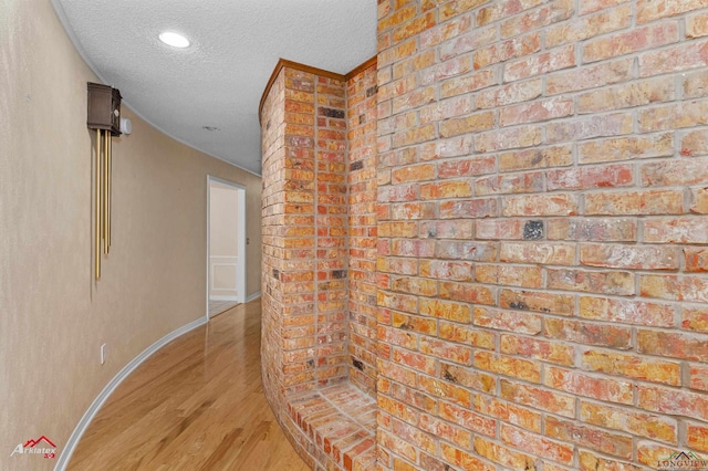 hallway featuring light wood-type flooring and a textured ceiling