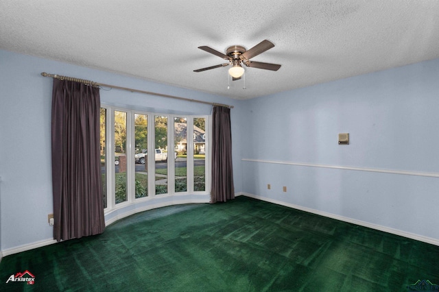 unfurnished room with ceiling fan, dark carpet, and a textured ceiling