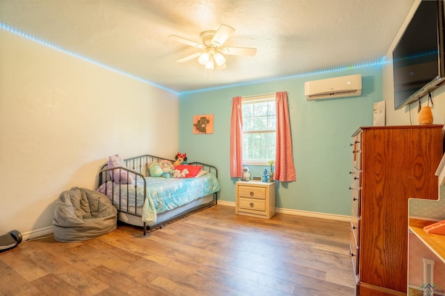 bedroom featuring ceiling fan, a wall mounted AC, and light wood-type flooring