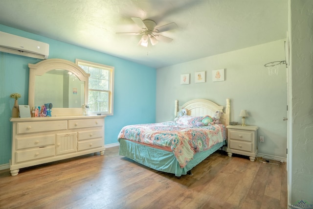 bedroom with light hardwood / wood-style flooring, a wall unit AC, and ceiling fan