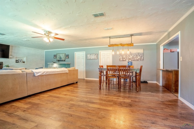 dining area with crown molding, wood-type flooring, a textured ceiling, and ceiling fan