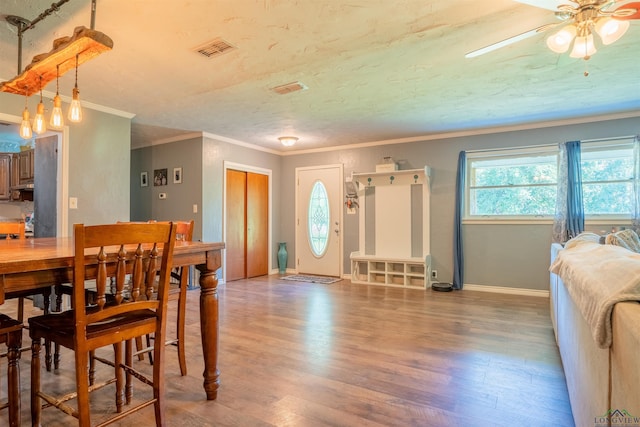 dining room featuring ornamental molding, hardwood / wood-style floors, ceiling fan, and a textured ceiling