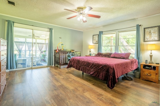 bedroom featuring ornamental molding, a textured ceiling, light hardwood / wood-style flooring, and access to outside