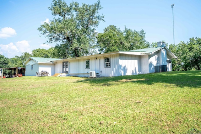 back of property featuring central AC unit and a yard