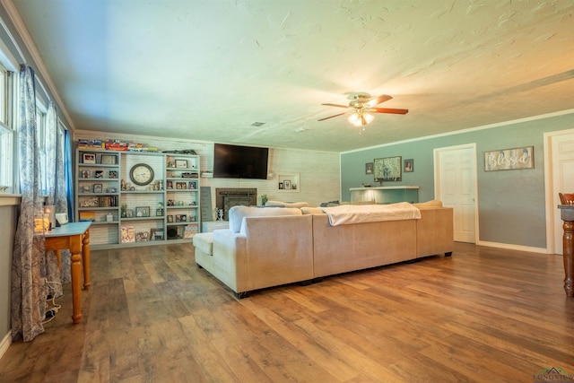 living room with ornamental molding, wood-type flooring, and a brick fireplace