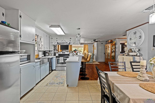 kitchen featuring ceiling fan, stainless steel appliances, light tile patterned flooring, pendant lighting, and white cabinets