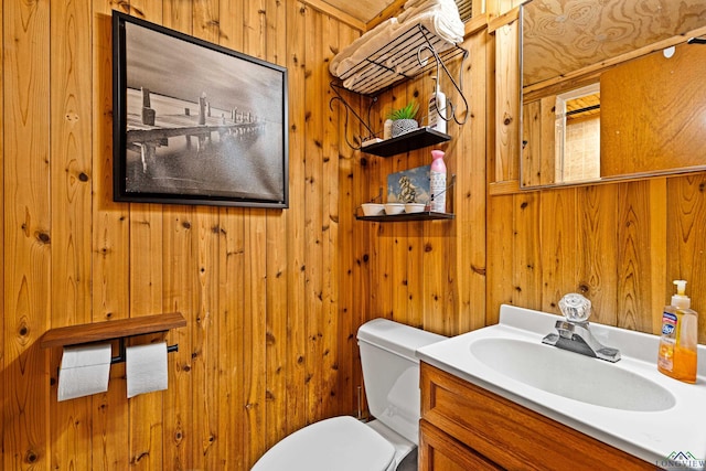 bathroom with vanity, wood walls, and toilet