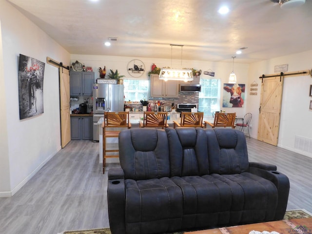 living room featuring a barn door and light hardwood / wood-style flooring