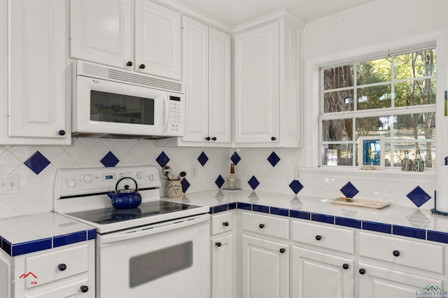 kitchen with white appliances, tile countertops, decorative backsplash, and white cabinets