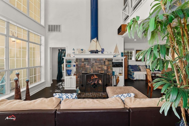 living room with a towering ceiling, dark wood-type flooring, and a fireplace